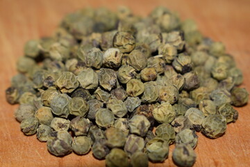 Green peppercorns close up over wooden table