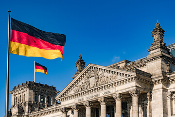 Fototapeta na wymiar The federal flag in front of the impressive Reichstag in Berlin as a symbol of democracy