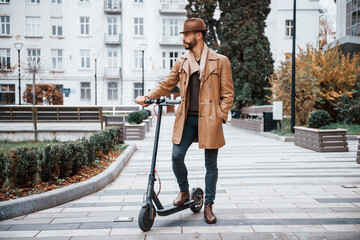On the electric scooter. Young male model in fashionable clothes is outdoors in the city at daytime