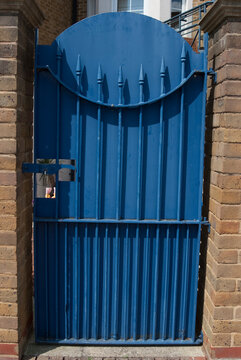 Closed and padlocked blue metal wrought iron gate.