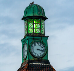 Old lighthouse with green lantern and a clock.