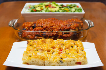 Freshly homemade focaccia bread on wood dinner table.