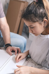 Fototapeta premium Father and daughter are assembling white furniture. Vertical shot. Selective focus