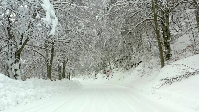 Strda di montagna innevata, in mezzo agli alberi coperti di neve.
Vista aerea di paesaggio invernale. Strada di montaggna sotto la neve in mezzo al bosco di pini