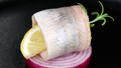 herring. marinated herring with rosemary sprig and onion on black plate