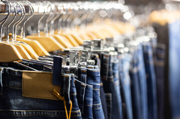 Fototapeta premium Row of hanged blue and black jeans on hangers in a shop.