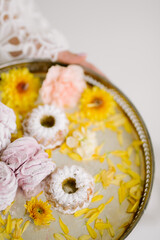 
the bride holds a tray with marshmallows and yellow flowers in her hands