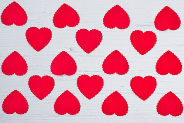 Top view of small red hearts made of paper evenly lined on a white old wooden background .Concept of texture, valentines day. Flat lay.