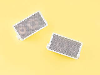 Retro gray audio music speakers on bright yellow background. Flat lay