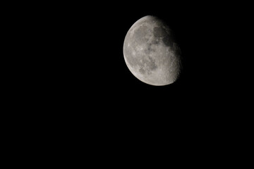 Big embossed Moon in night sky. Single shot of an earth satellite through a telescope. Astrophotography of the illuminated relief surface of the Moon.