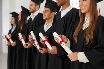 Students at the graduation ceremony. Cropped image of a group of multiethnic people standing in a row and holding scrolls of diplomas in their hands. Concept of a new stage of life. Selective focus.
