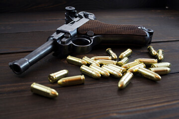 Historic Luger P08 Parabellum handgun, old soviet TT handgun and shiny 9 mm bullets on wooden vintage background