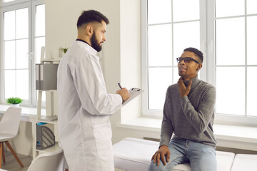 Patient telling doctor about painful flu or cold symptoms during visit to hospital. Young...