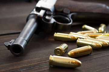 Historic Luger P08 Parabellum handgun, old soviet TT handgun and shiny 9 mm bullets on wooden vintage background