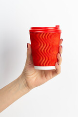 Female hand holding disposable coffee cup red colour on white background.