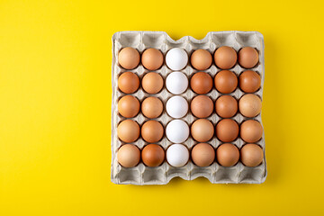 Nice big rural fresh eggs in cardboard egg box holder with colorful yellow background.