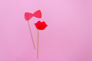 flatlay false paper photo stand props: bow tie and red lips on pink background copyspace for Valentine's day greeting card