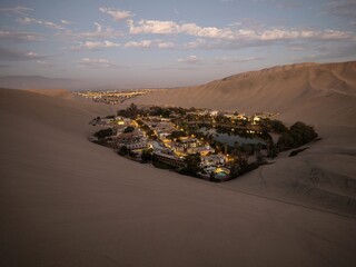 Panoramic postcard view of Huacachina oasis town village desert dry sand dunes texture pattern Ica...