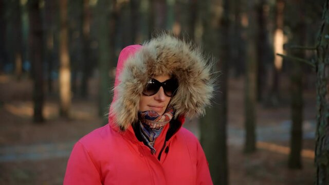 Girl In Red Parka Walking In Winter Greenwood.Carefree Female Exploring Wood Forest In Winter Sunny Time.Active Woman In Parka Walking In Pine Forest.Holiday Vacation Tourist Journey Trip In Cold Day.