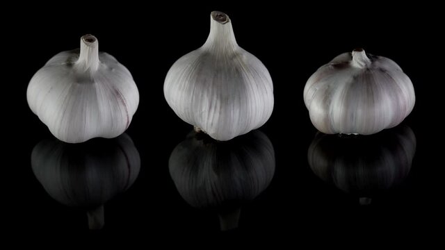 garlic at black background, three bulbs are rotating, spices for cooking