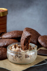 Fluffy chocolate brownie cookie placed inside a peanut butter ice cream bowl. Pile of healthy homemade gluten free chocolate chip cookies in the background.