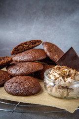 Pile of fluffy chocolate brownie cookies with broken cookies on top served with peanut butter ice cream and dark chocolate. Healthy homemade gluten free chocolate chip cookies on a cooling rack.
