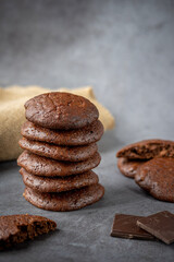 Stack of fluffy chocolate brownie cookies along with broken cookie into half, pieces of dark...