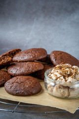 Pile of fluffy chocolate brownie cookies served with peanut butter ice cream in a glass jar. Healthy homemade gluten free chocolate chip cookies on a cooling rack.