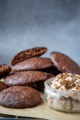 Pile of fluffy chocolate brownie cookies served with peanut butter ice cream in a glass jar. Healthy homemade gluten free chocolate chip cookies on a cooling rack.