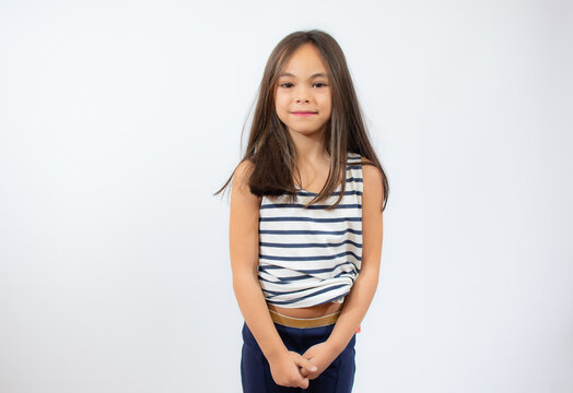 Beautiful little girl in striped t-shirt smiling over white background.