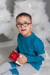 A boy with glasses with Down syndrome sits at a table and plays with toys