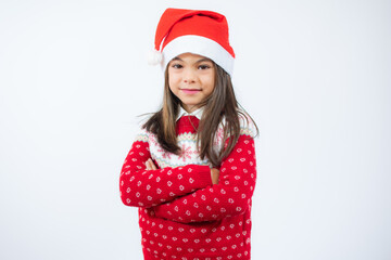Beautiful little girl in santa hat with arms folded over white background.