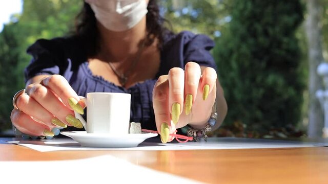 Brunette woman drinking turkish coffee from a cup in a cafe on the street