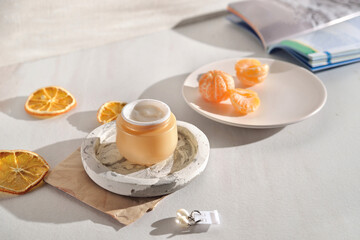 Beauty lifestyle background with Opened Jar of face cream and fresh tangerines.  winter skin care concept