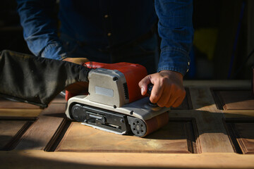 The carpenter is sanding the wood,The carpenter is smoothing the wood to remove the burr.