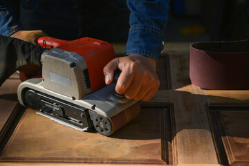 The carpenter is sanding the wood,The carpenter is smoothing the wood to remove the burr.