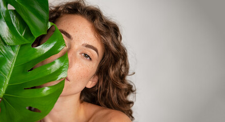 Beautiful woman with natural make up and green leaves