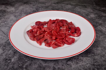Raw beef meat cut into thin strips for beef Stroganoff on white plate