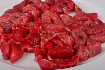 Raw beef meat cut into thin strips for beef Stroganoff on white plate