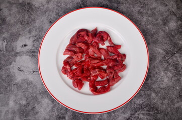 Raw beef meat cut into thin strips for beef Stroganoff on white plate