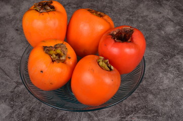 Group of Ripe orange persimmon fruit.Persimmon fruits in plate, rustic background, Hurma fruit