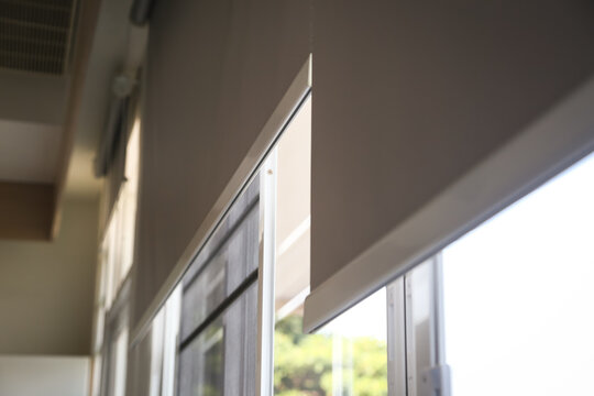 Details of white fabric roller blinds on the plastic window in the living room. 