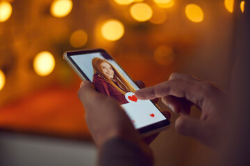 Find love online concept. Single man pressing red heart like button below attractive young woman's...