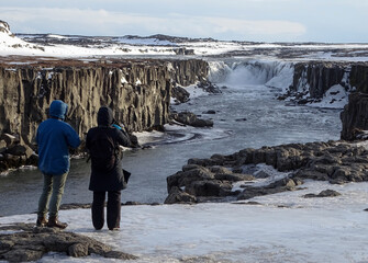 Couple standing at Godafoss waterfall in Iceland.