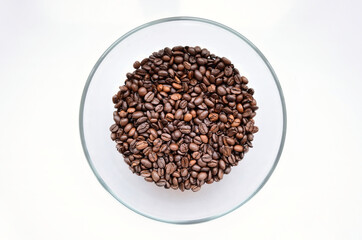 Coffee beans in a bowl on a white background. A lot of roasted coffee in a black and red plate. The wide photo at the top.