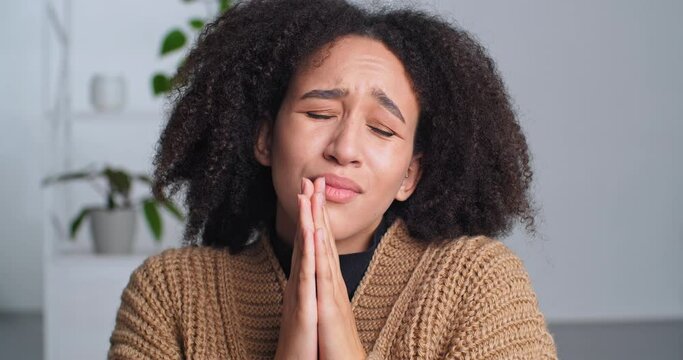 Cute sly african american black woman folds her hands in request pleading makes gesture of apology asks for forgiveness grimaces face expresses pity, emotional lady female face looking at camera