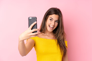 Fototapeta premium Teenager Brazilian girl over isolated pink background making a selfie