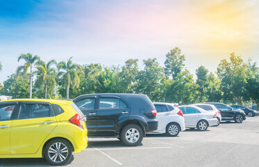 Fototapeta premium Cars parking in asphalt parking lot in a row with blue sky background. Outdoor parking lot with fresh ozone, green nature environment of transportation and technology