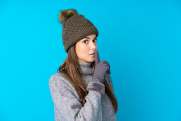 Teenager girl with winter hat over isolated blue background doing silence gesture