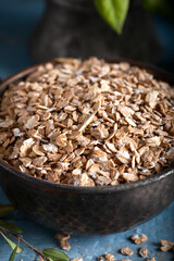 Healthy cereal flakes in a ceramic bowl. Rye flakes in a bowl on stone blue wooden background.